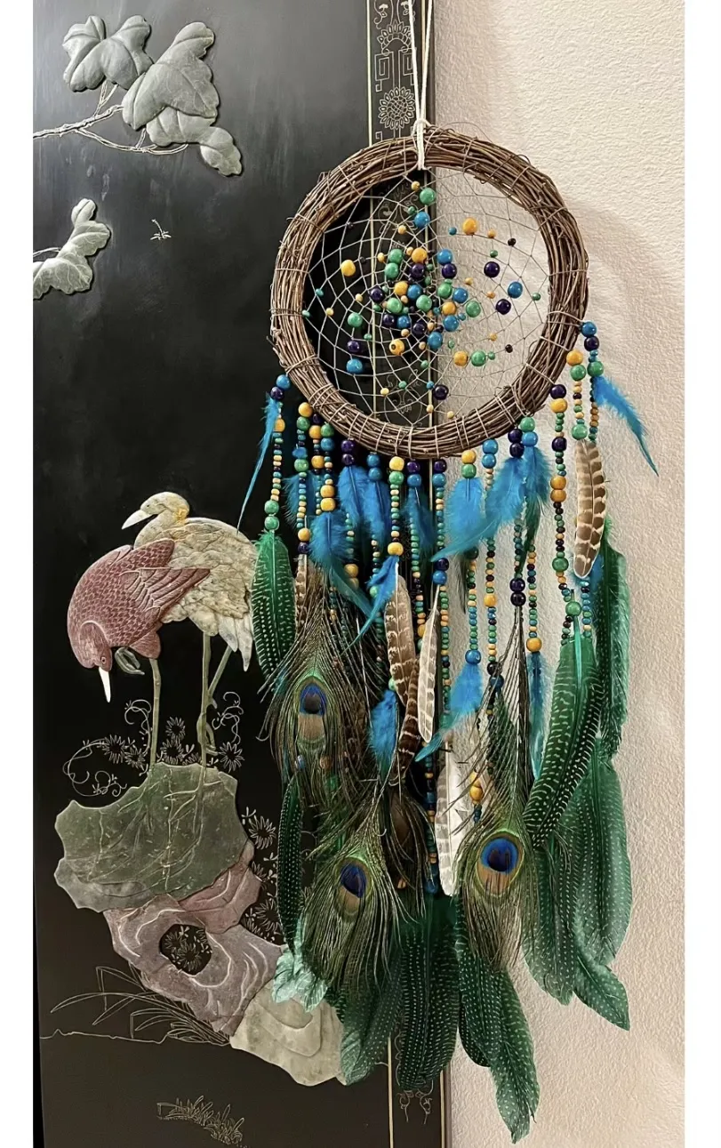 A beautifully handcrafted dream catcher with flowing feathers and beads, symbolizing protection and serenity in a bedroom setting.