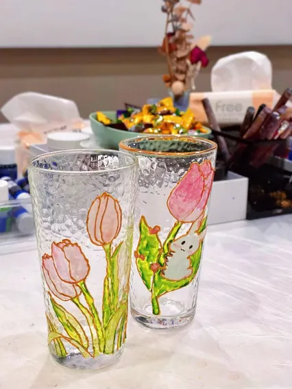 A colorful painted glass cup featuring floral designs.